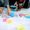 person in gray shirt holding white printer paper collaborative logo design, team working together, digital tools